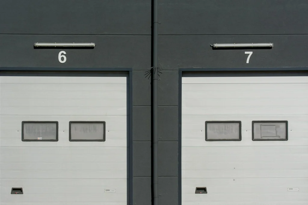 2 commercial garage doors 2 commercial garage doors with the number 6 above the left one and the number 7 above the right one.